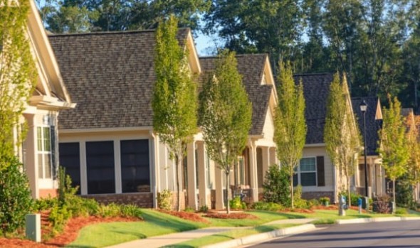 A neighborhood of similarly-designed houses, each with young trees outside